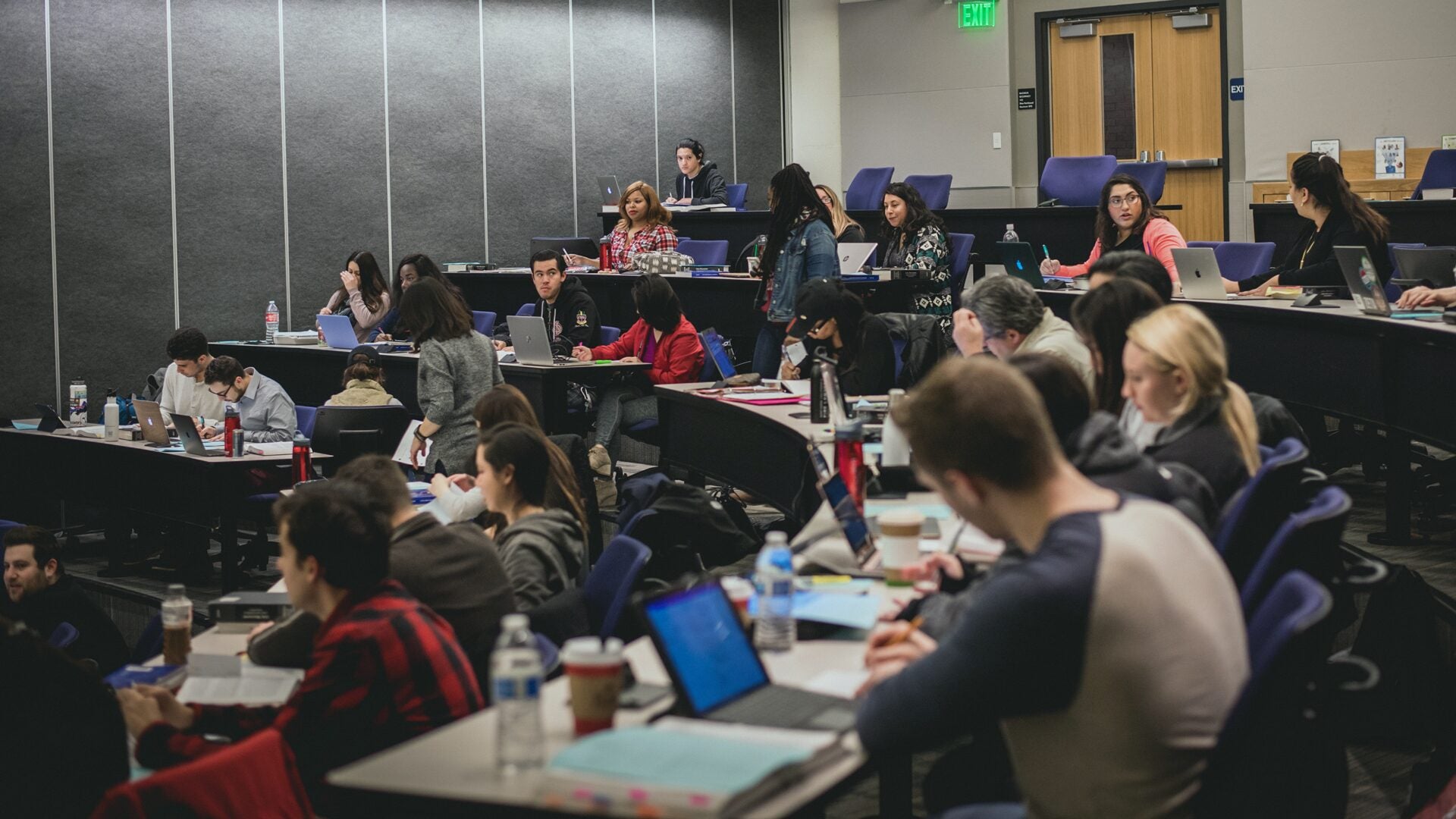 Large classroom filled with students working on laptops and taking notes.